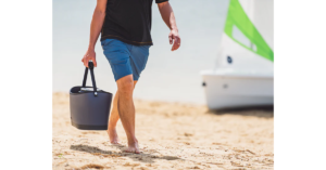 A person carrying the RovR KEEPR Cooler Caddy along the beach.