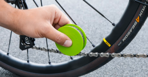 Green disc bike chain care tool lubricating a chain with just a swipe.