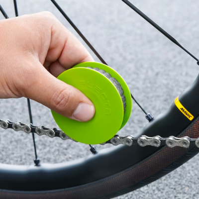 Green disc bike chain care tool lubricating a chain with just a swipe.